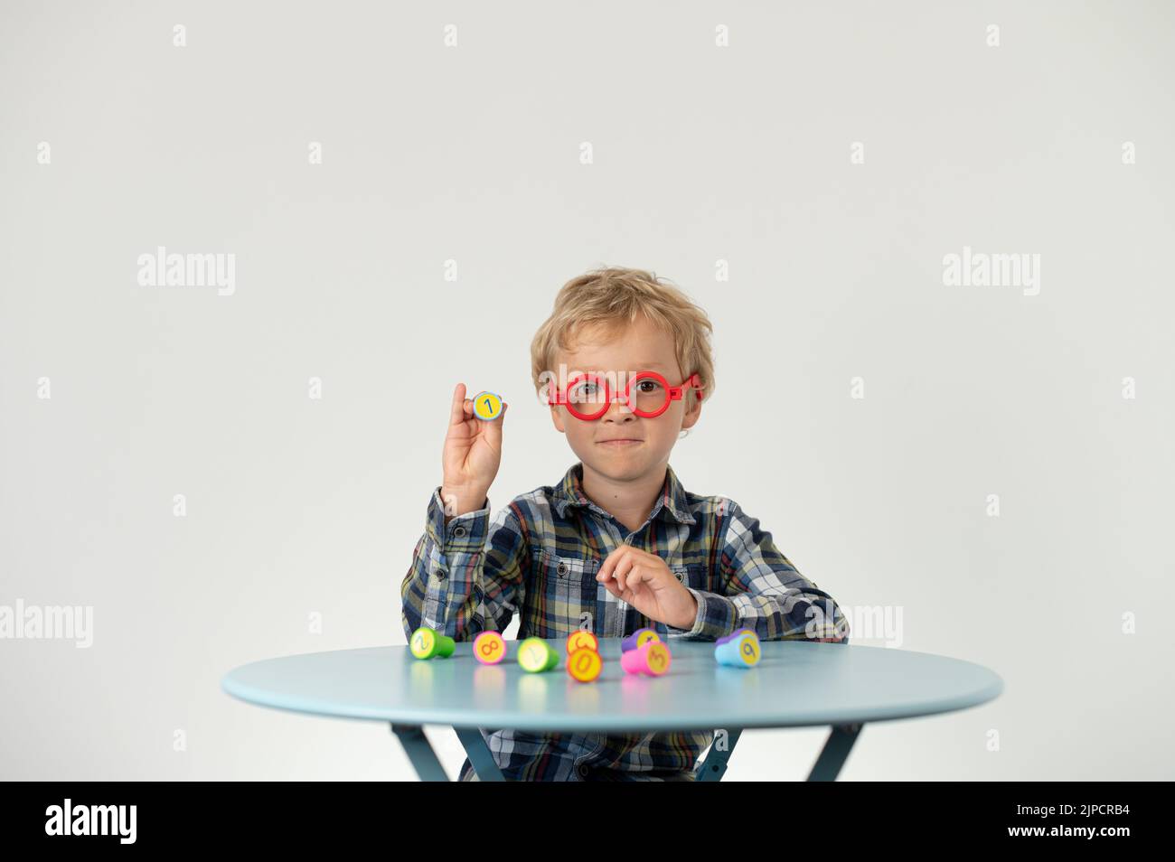 Boy sitting at a table, showing lotto number, school grade Stock Photo