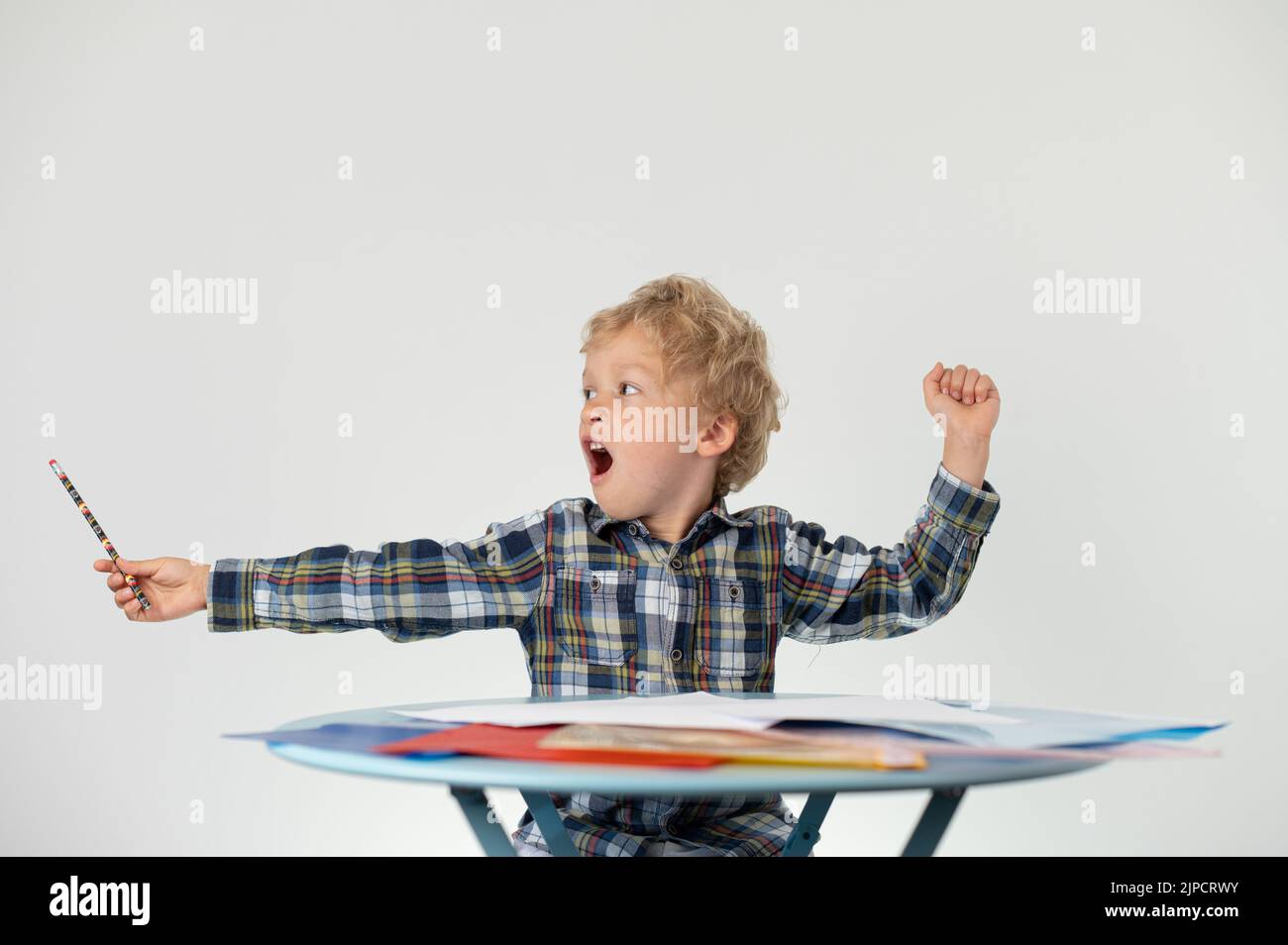 Boy with a pencil yawning at a table, school education Stock Photo