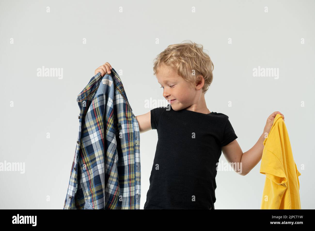 Boy deciding what cloth to put on Stock Photo