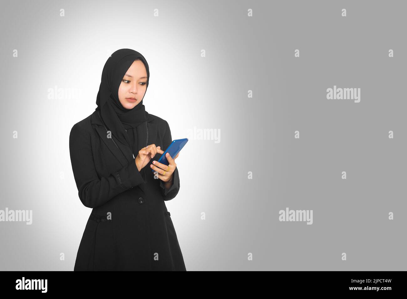 Beautiful young Muslim business woman wearing hijab holding smartphone ...