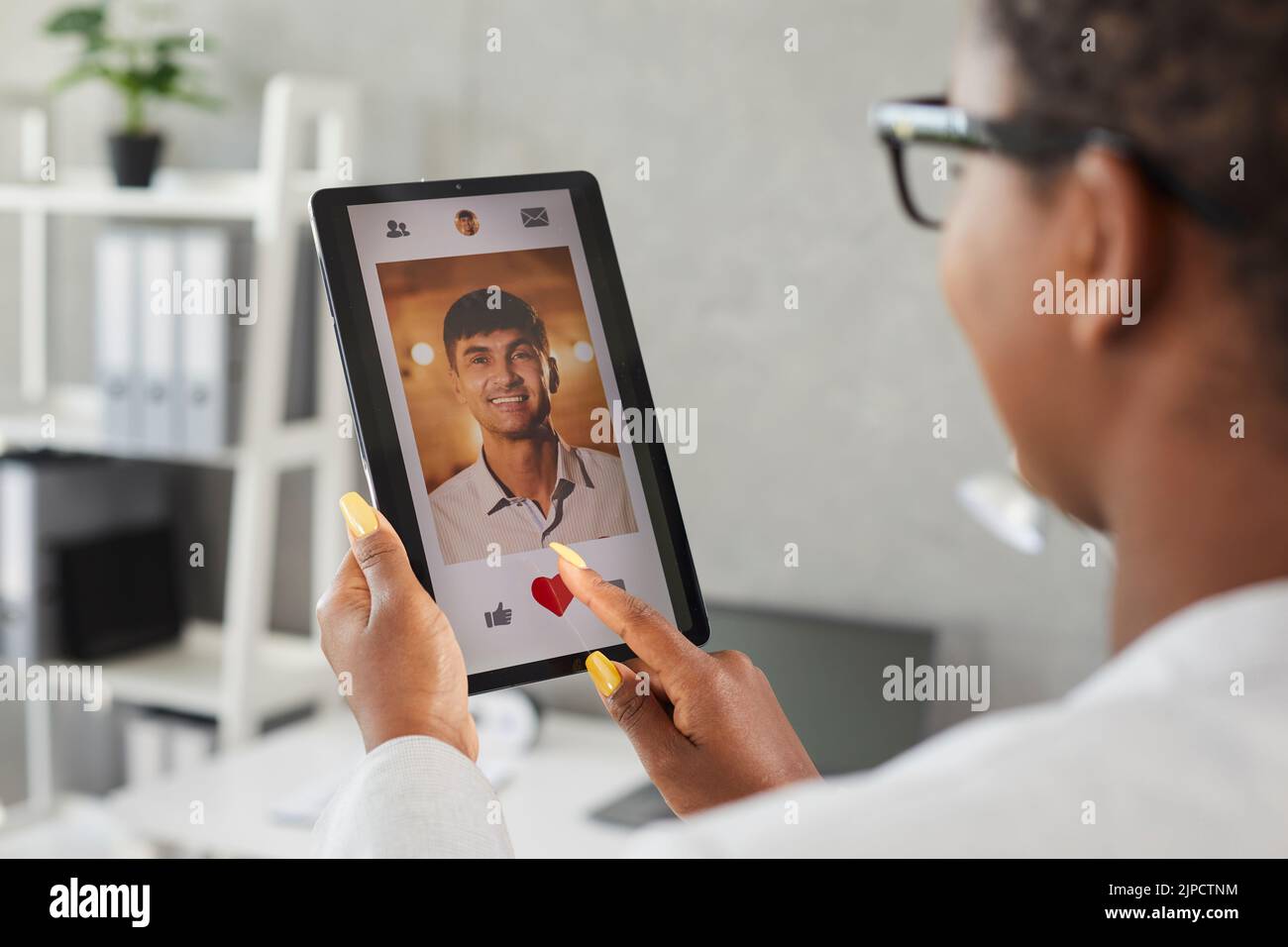 Woman uses digital tablet and likes photo of young man on online dating app or website Stock Photo