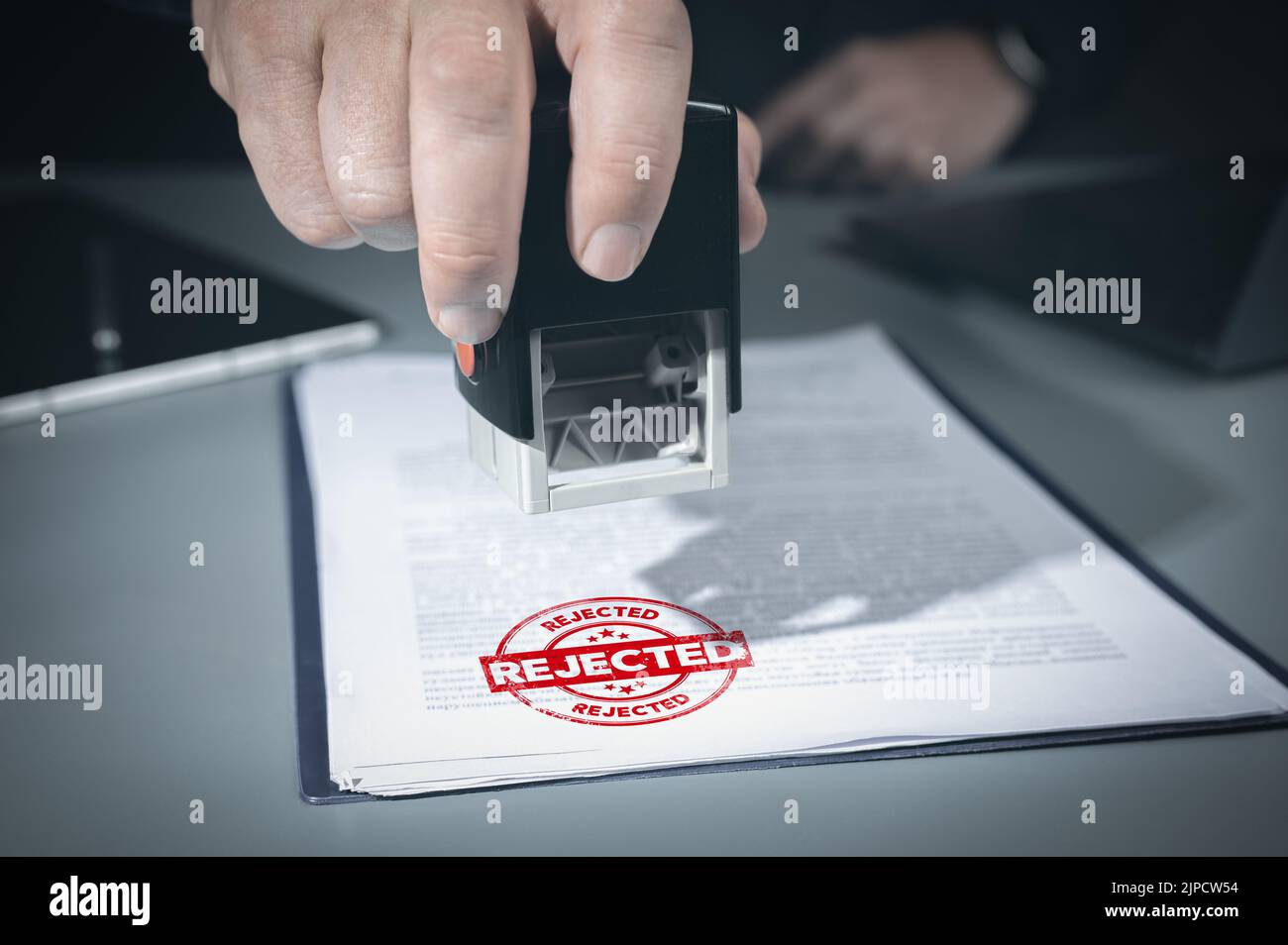 Close-up Of Person Hand Stamping With Rejected Stamp On Text denied Document At Desk, Contract Form Paper. Businessman signing business project reject Stock Photo