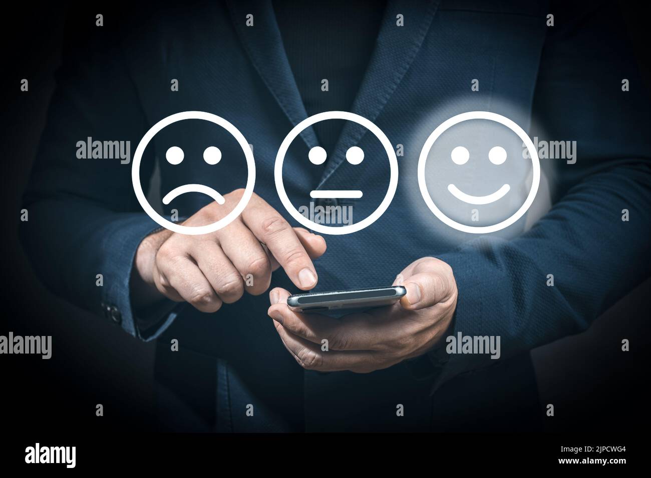 Businessman using cellphone for select smiley face icon for client evaluation and customer satisfaction after use product and service concept. Man sma Stock Photo