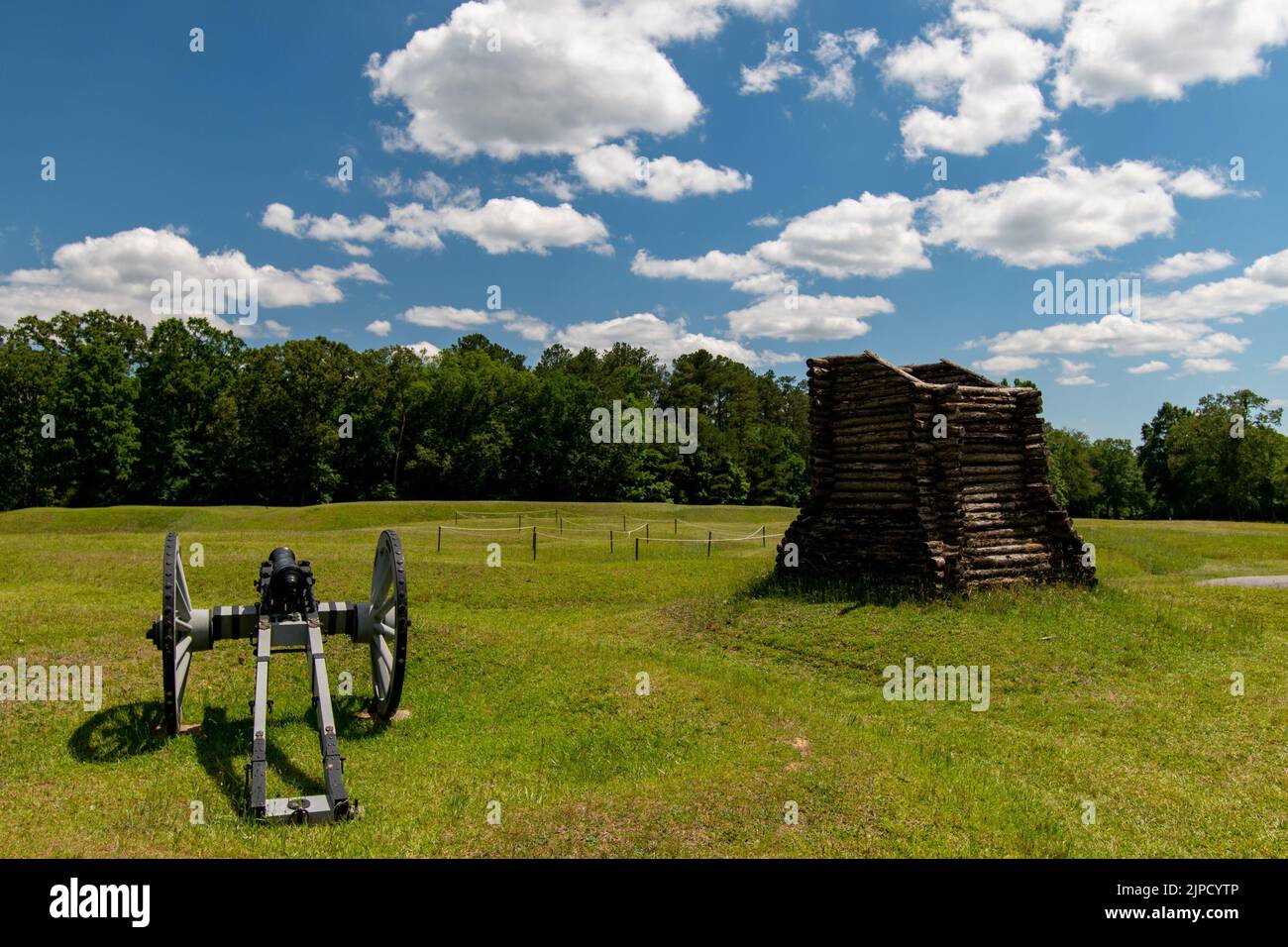 A Gatling gun set in an open field with a wooden little fort next to it Stock Photo
