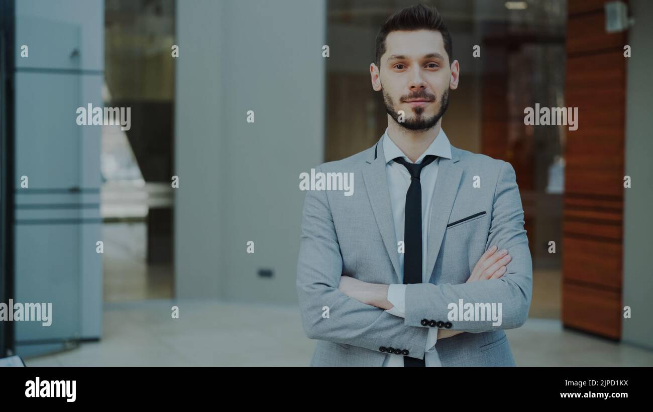 Portrait of successful young smiling businessman looking into camera in ...