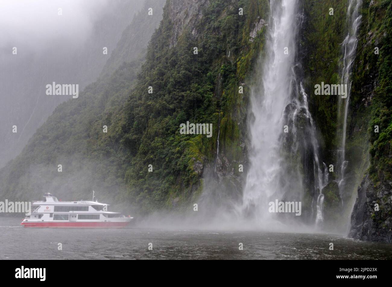 The Cruise ship, Pride of Milford of Red Ferries edges closer to the 155 m tall Stirling Falls for the benefit of tourists on Milford Sound in Fiordland Stock Photo