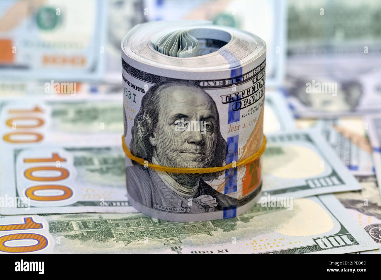 Bundle of money roll of dollars on a pile of 100 banknotes, stack of
