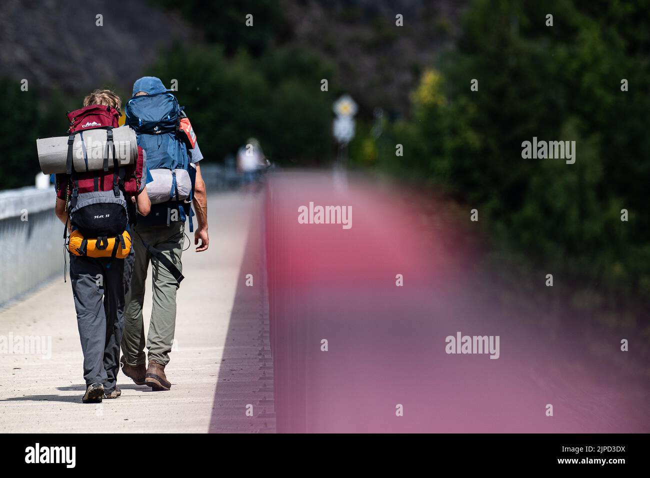 Schulenberg, Germany. 17th Aug, 2022. Hikers with backpacks walk across a bridge at the Okertalsperre in the Harz Mountains. Credit: Swen Pförtner/dpa/Alamy Live News Stock Photo
