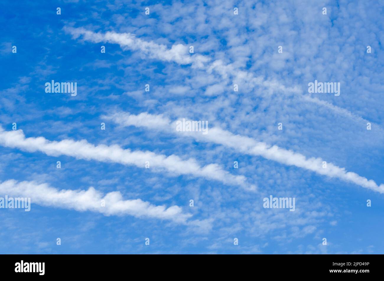 Condensation trails of aircraft and clouds in the blue sky Stock Photo