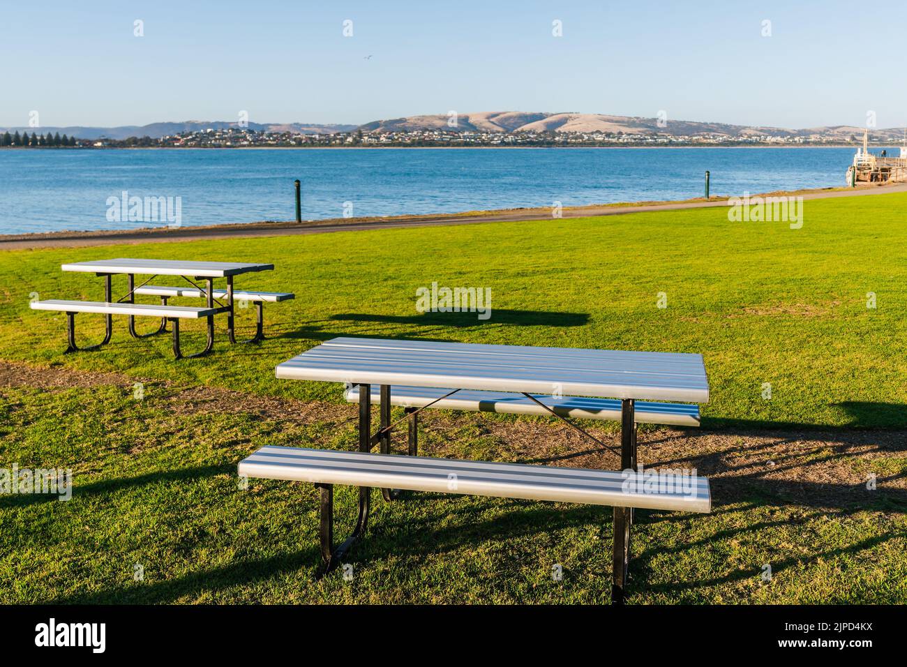 Picnic tables with a view on Granite Island seashore at sunset, South Australia Stock Photo