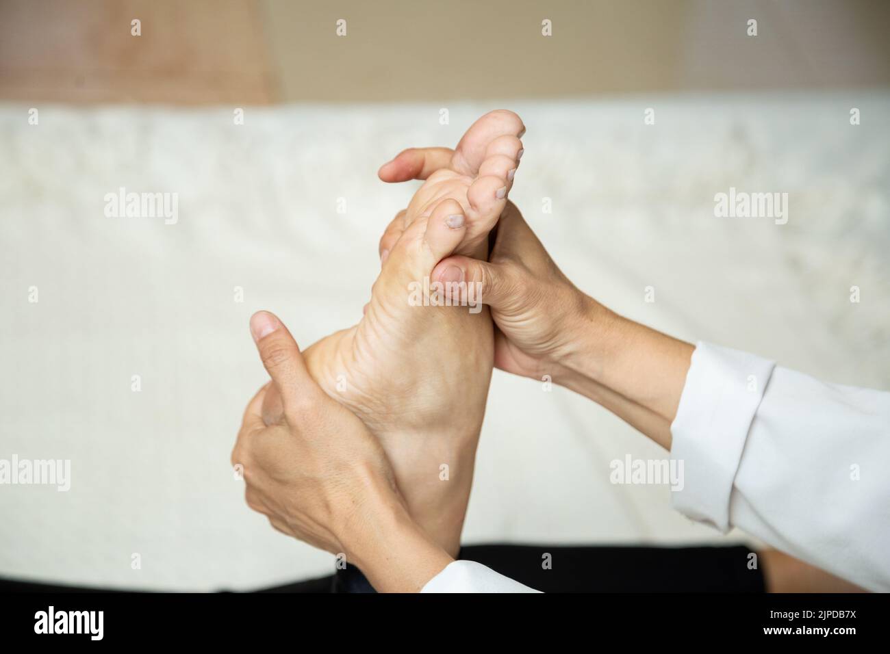 Goiânia, Goias, Brazil – July 18, 2022: Closeup of massage therapist hands applying therapeutic massage to a patient's foot. Stock Photo
