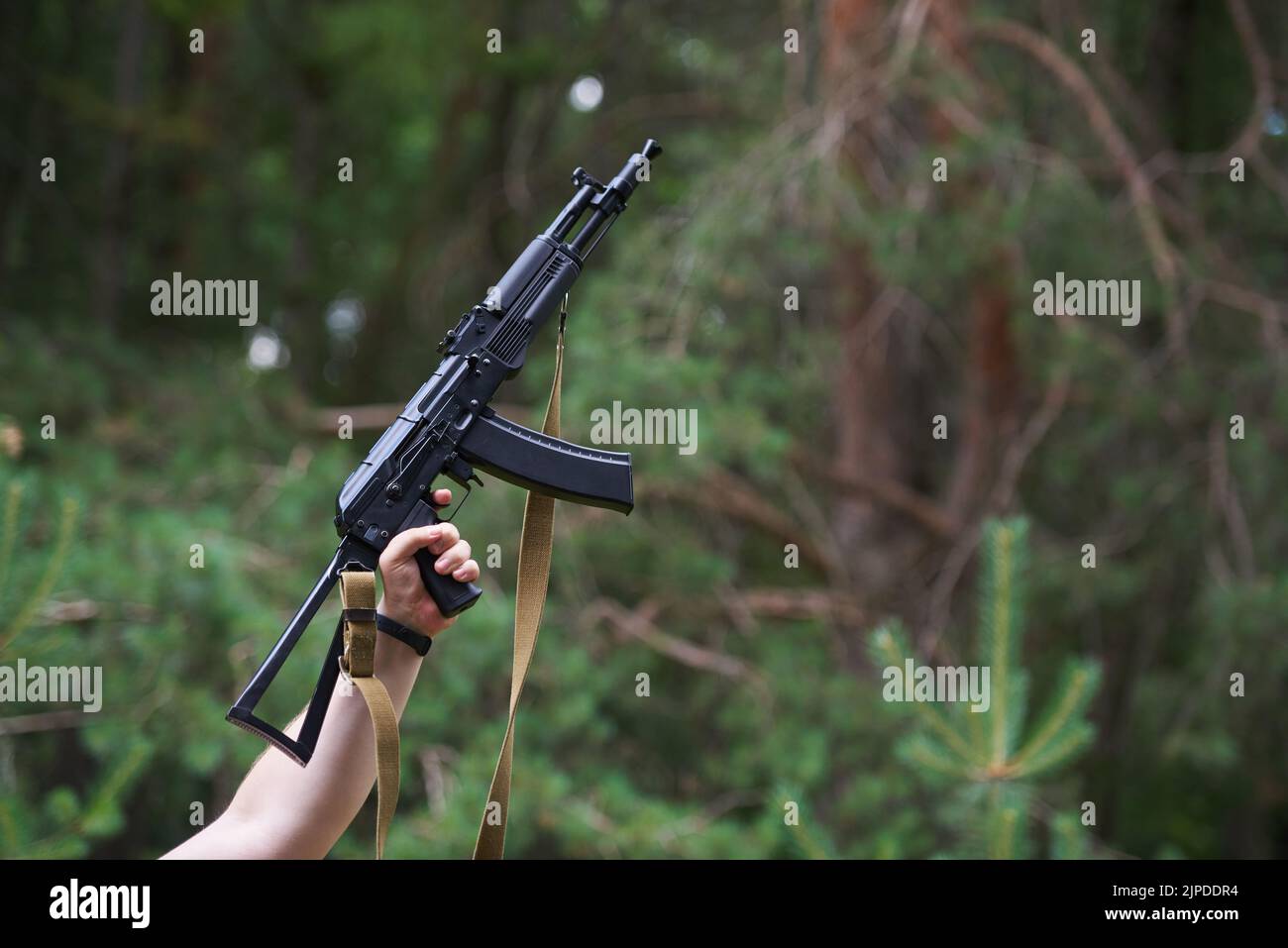 STARIY OSKOL, RUSSIA - JULY 3, 2022: Russian Kalashnikov assault rifle of AK-74 in male hands on the background of the forest Stock Photo