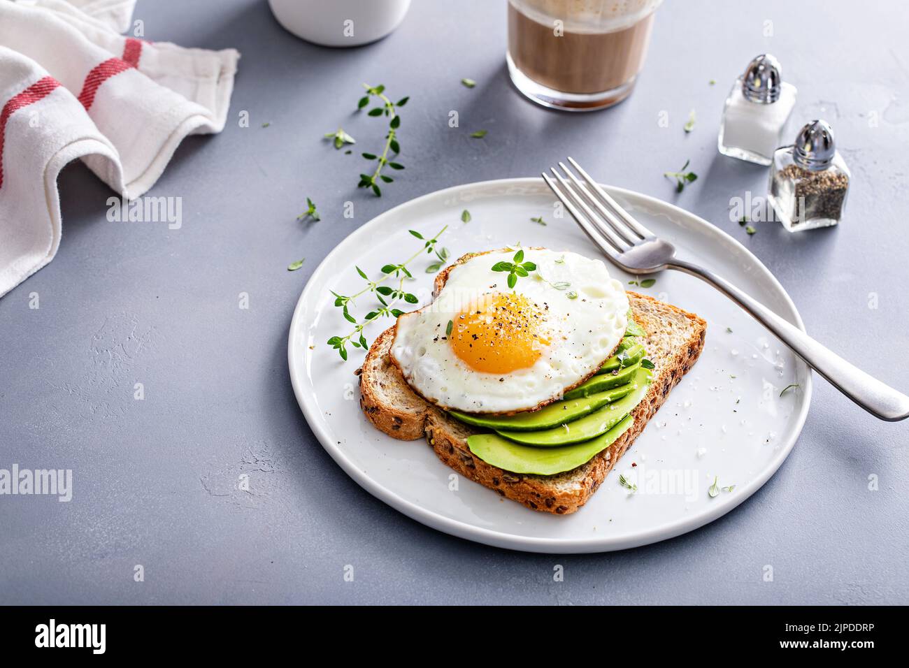 Avocado toast on a toasted multigrain bread with a fried egg Stock Photo