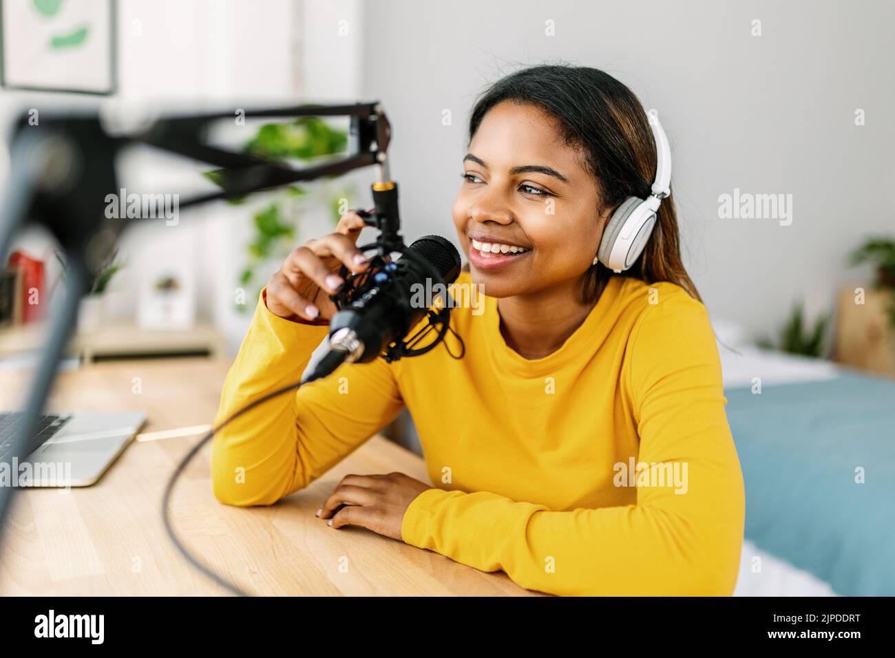 Young ethnic woman recording radio podcast from home studio Stock Photo