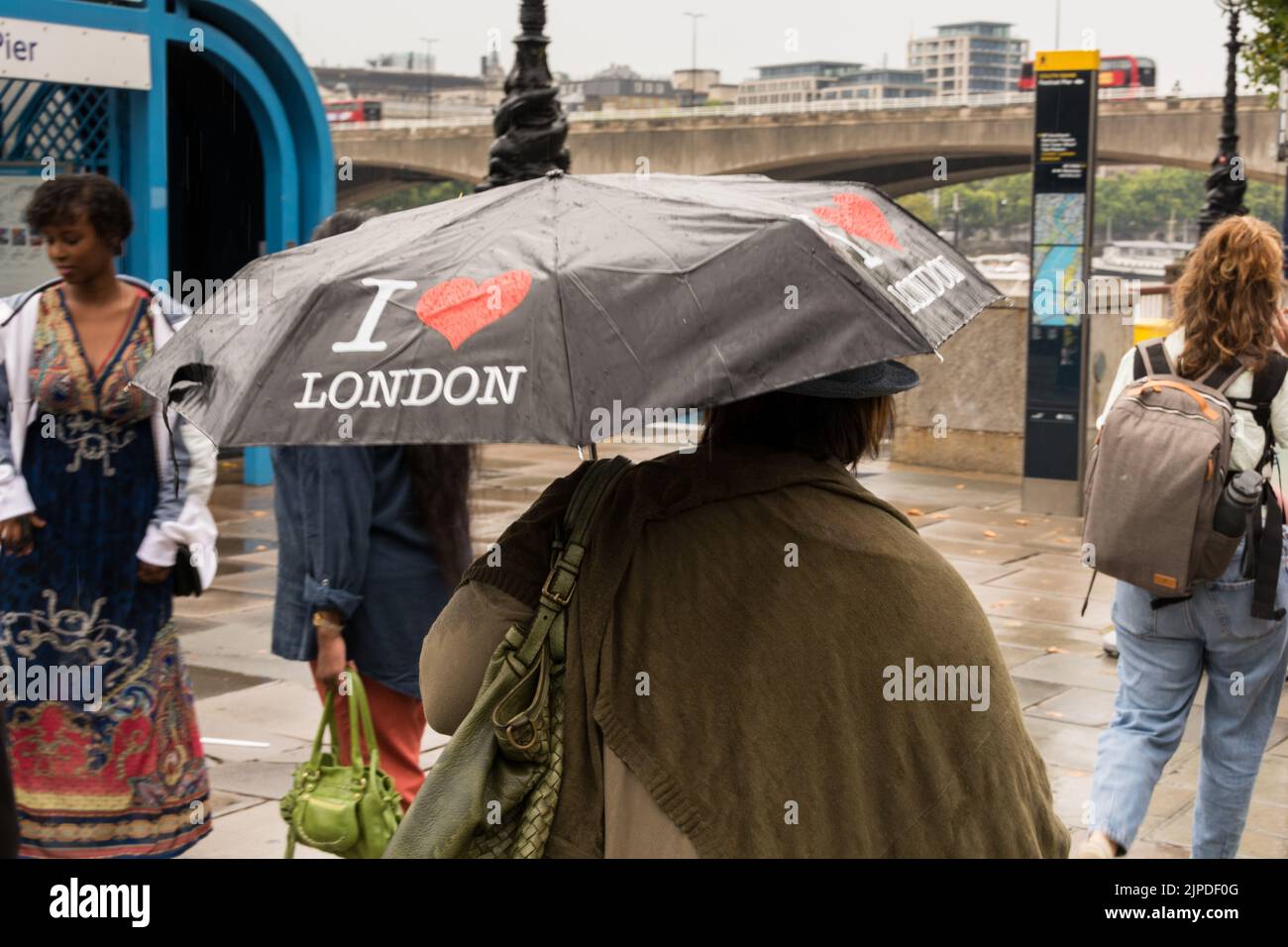 London, England, UK. 16 August 2022.  The drought and heatwave in the UK is finally over - An I Love London tourist's umbrella shielding a woman  from some all too rare rain on London's Southbank. © Benjamin John Stock Photo