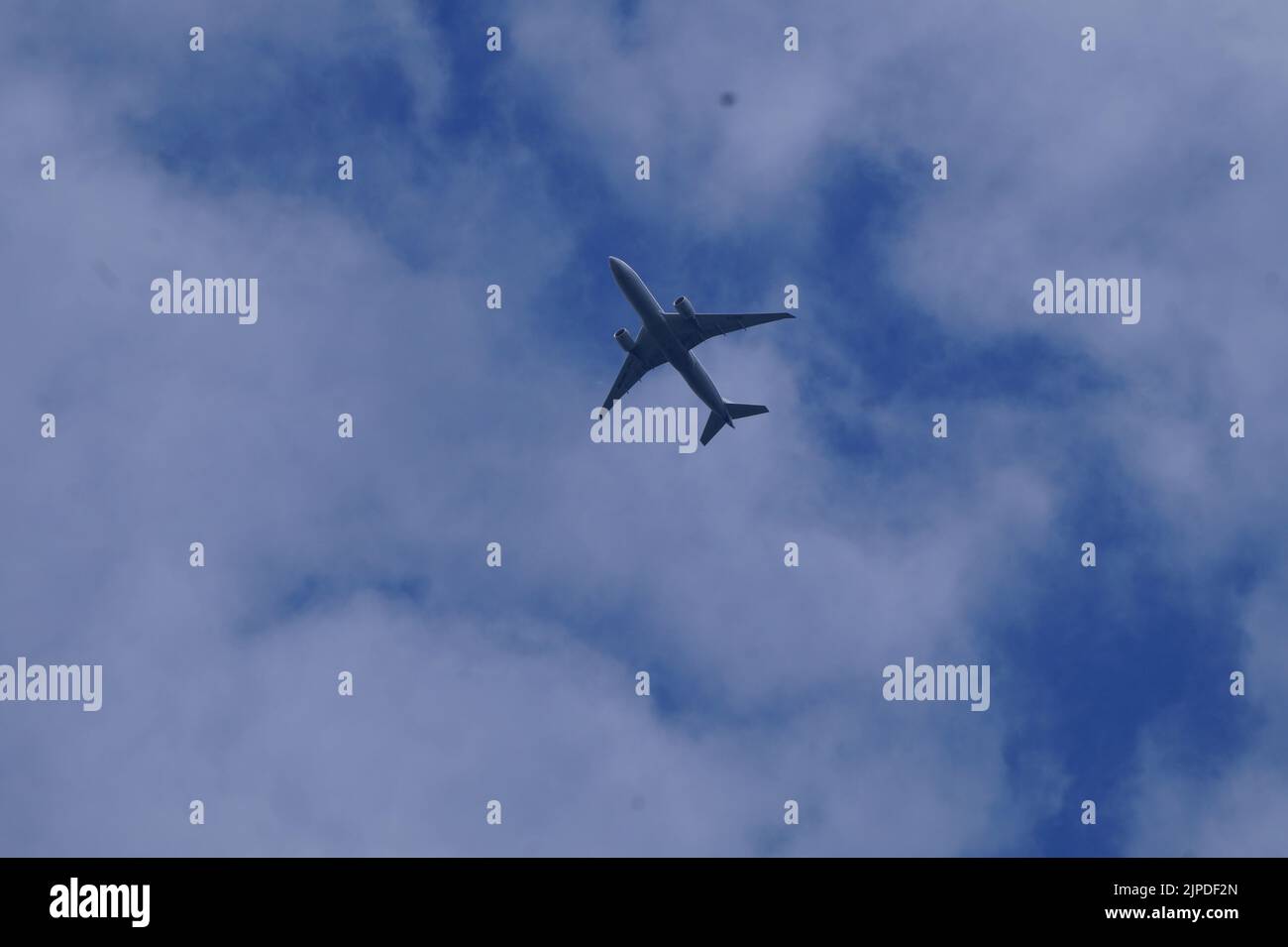 The view of a plane flying in the blue cloudy sky Stock Photo - Alamy