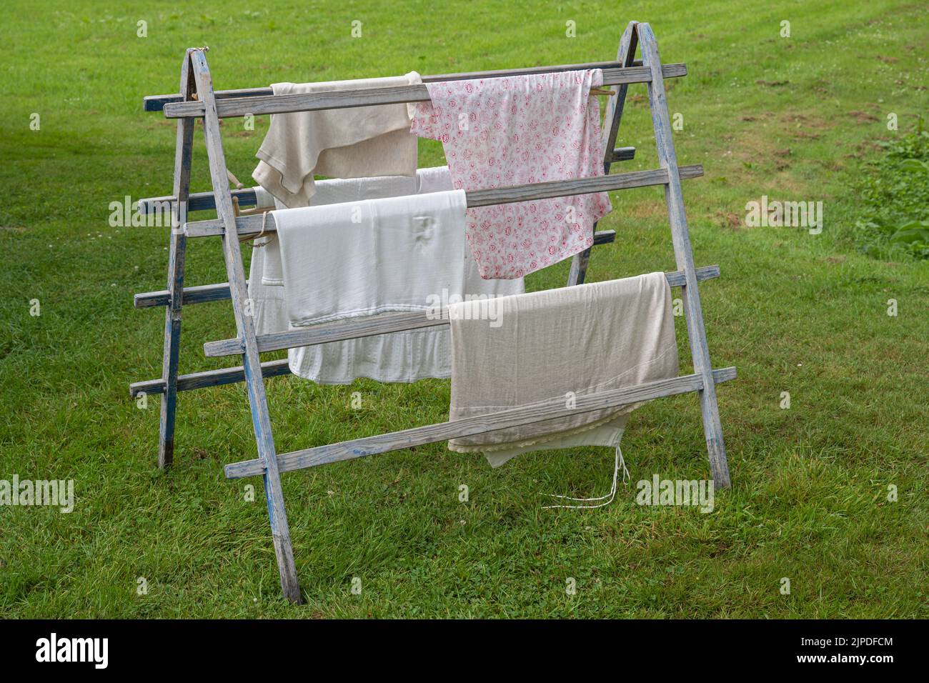 Oldfashioned authentic standing wooden laundry rack with clothes in