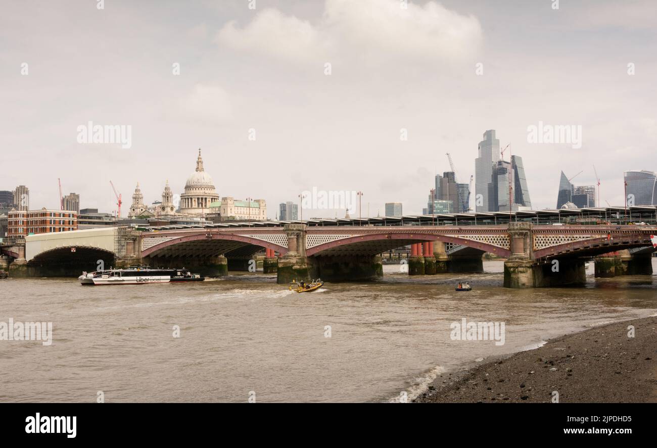 An Uber Boat passing under the new Blackfriars Station Railway bridge with St Paul's Cathedral and the City of London skyline in the background Stock Photo