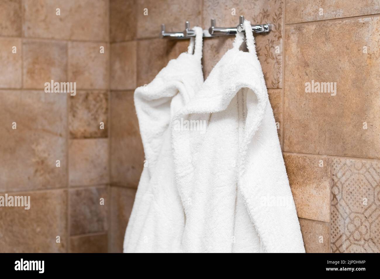 Fresh white bathrobes hanging on hooks in the bathroom in hotel room Stock Photo Alamy