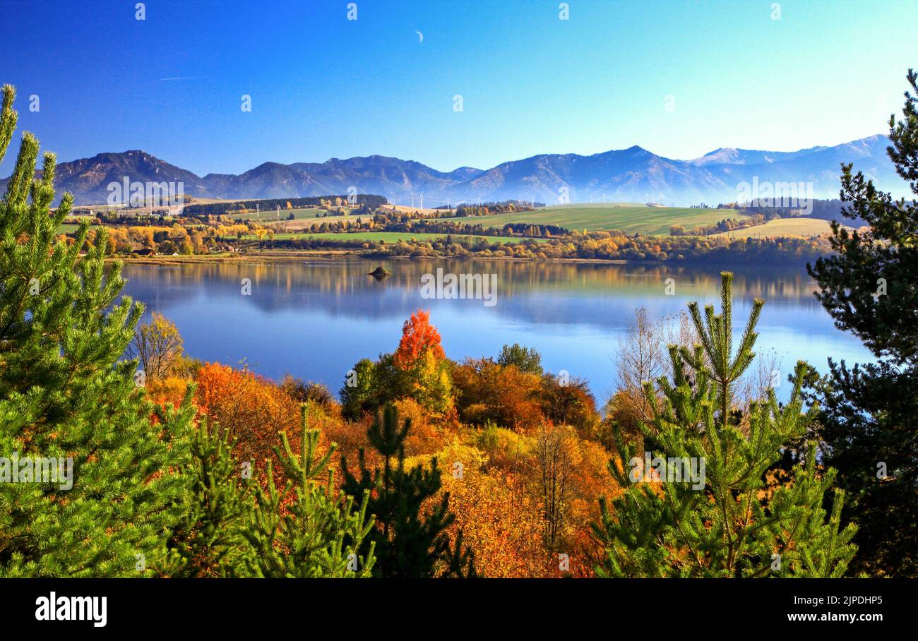 Autumn trees and mirror reflection of mountains in dam Lipttovska Mara, Slovakia Stock Photo