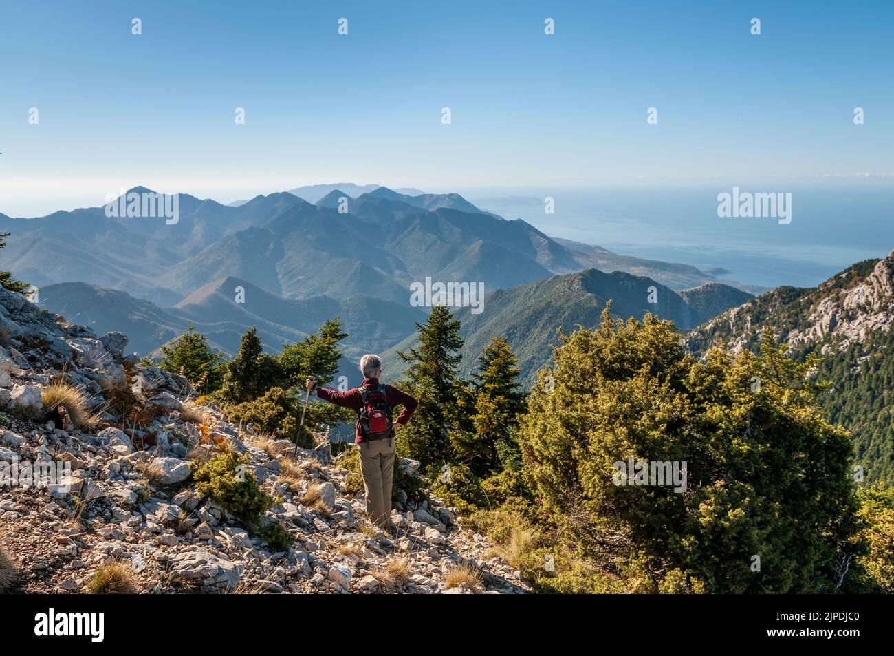 A walker looks down on the Mani Peninsula from Mavrovouna hill above Milea in the Taygetos mountains, Southern Peloponnese, Greece. Stock Photo