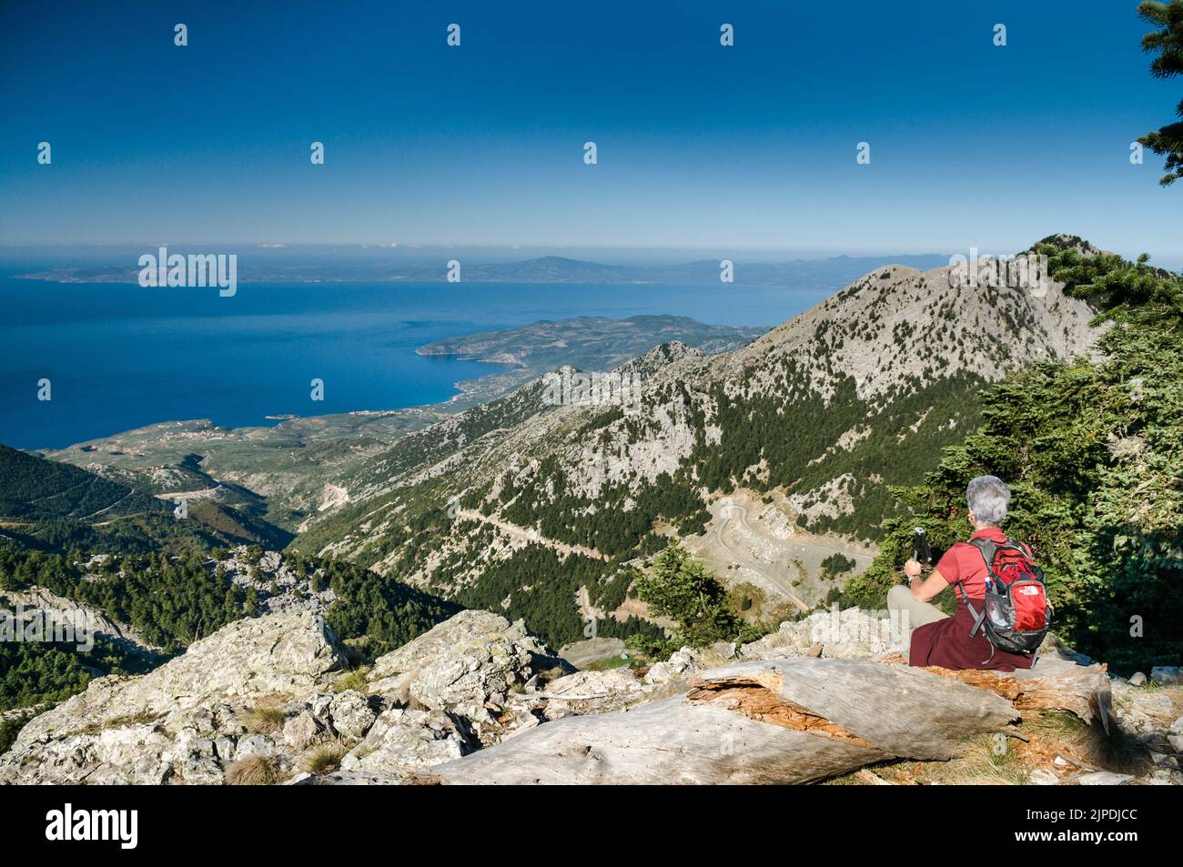 A walker looks down on the Outer Mani coast towards Kardamyli (centre) and across the Gulf of Messini, from Mavrovuna hill in the Taygetos mountains, Stock Photo