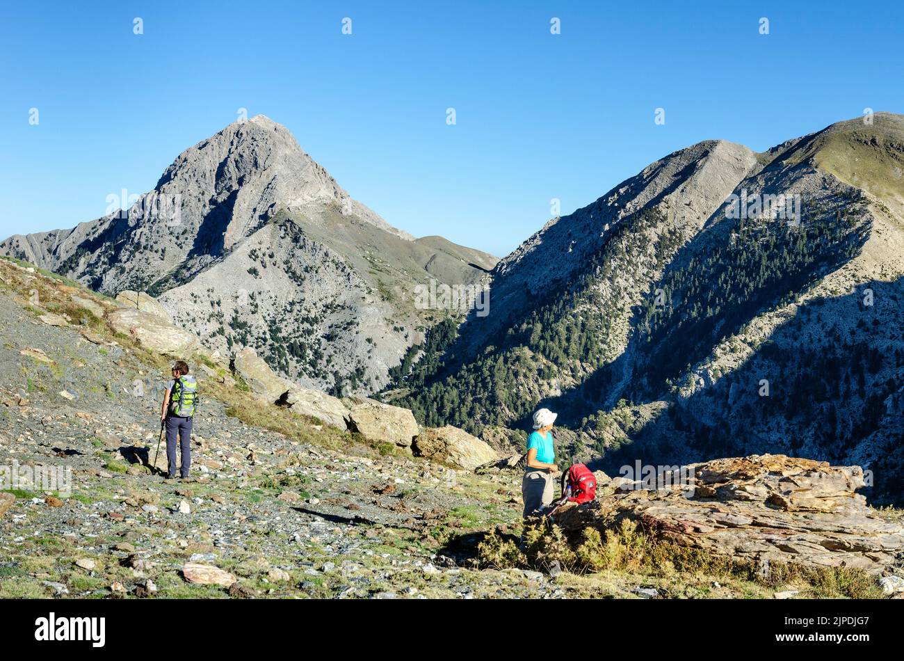 Walkers taking in the view   on Musgia pass, looking toward the peak of Hasalmeno, in the Taygetos mountains,  Southern Peloponnese, Greece. Stock Photo
