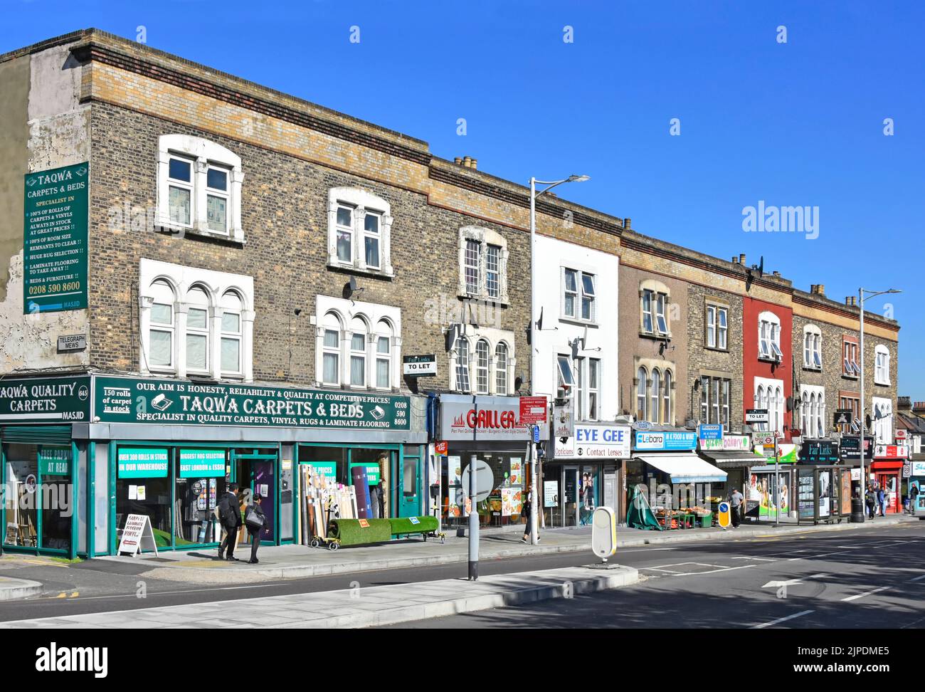 Street scene of Seven Kings High Road shopping parade with two storey residential apartment flat homes above shops in Redbridge East London England UK Stock Photo