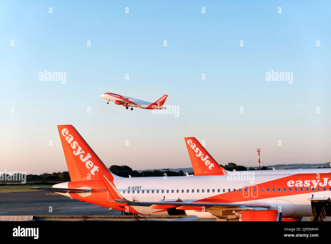 An EasyJet plane taking off from Bristol airport.  Another EasyJet plane is parked on the runway. The companies logo and branding are clearly shown. Stock Photo