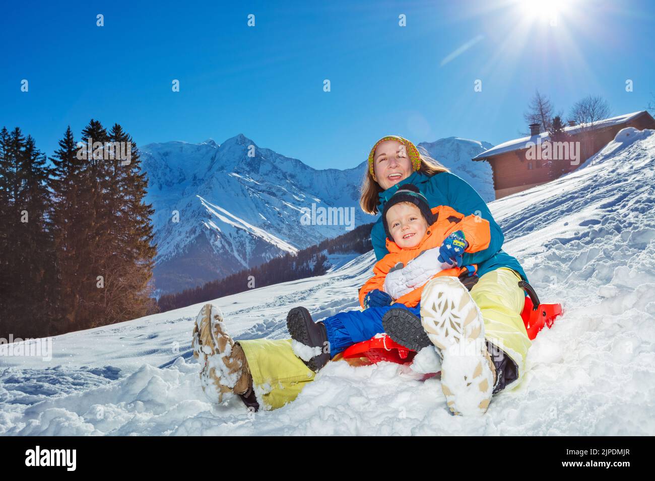 Mother with little boy together sit in the sledge go downhill Stock Photo
