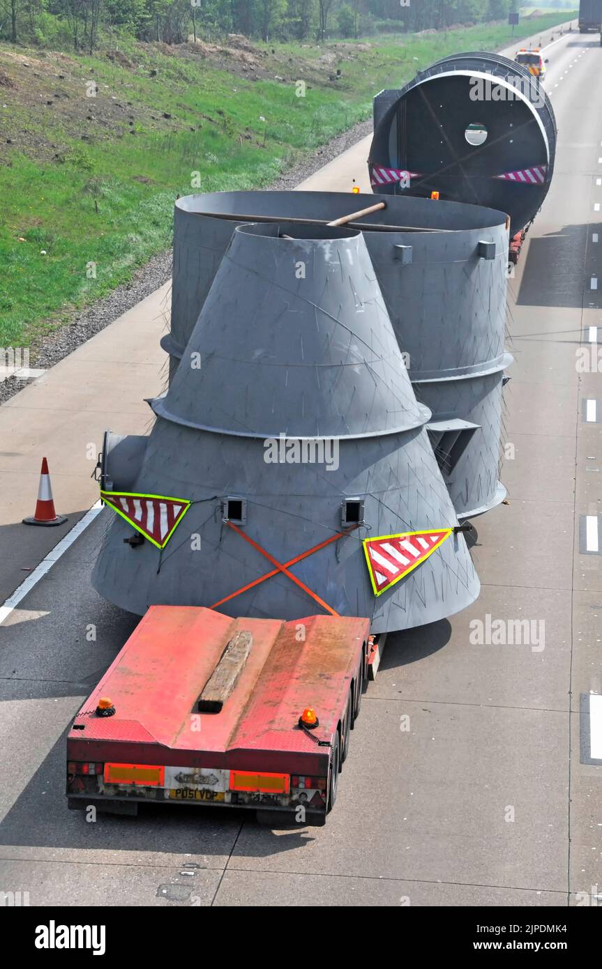 Aerial view of wide oversize load on specialised low loader trailers unusual shaped industrial components moving slowly on two lanes of UK motorway Stock Photo