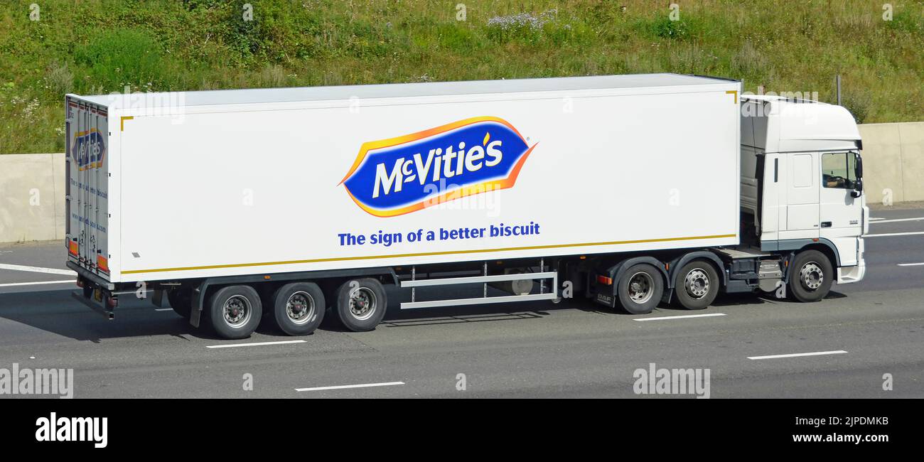 McVities biscuit manufacturing business advertising logo on side view articulated trailer towed by white hgv lorry truck driving on UK motorway road Stock Photo