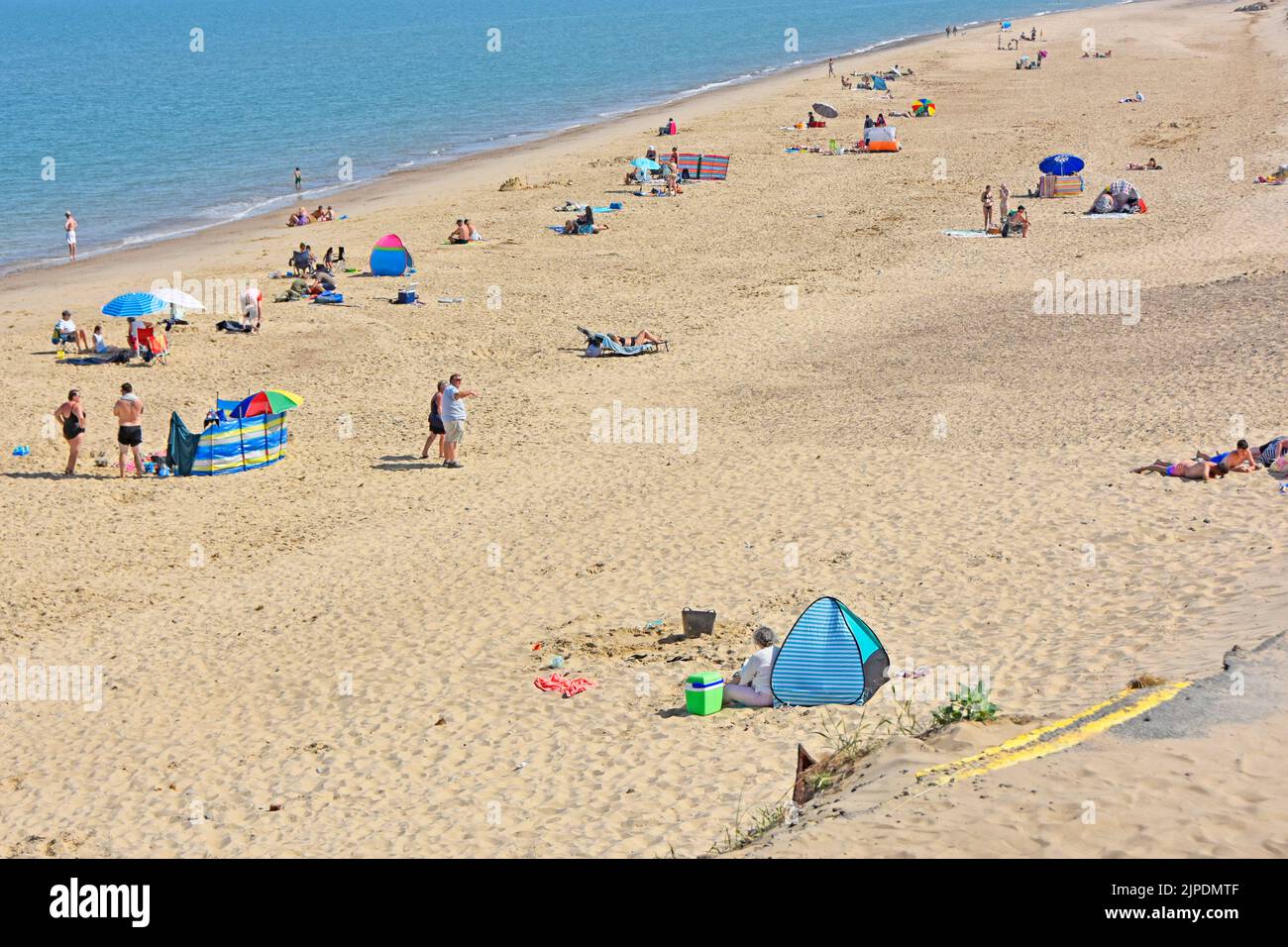 Holiday visitors to Winterton-on-Sea on beach below double yellow lines left after 2021 storm erosion sent road & car park into North Sea Norfolk UK Stock Photo