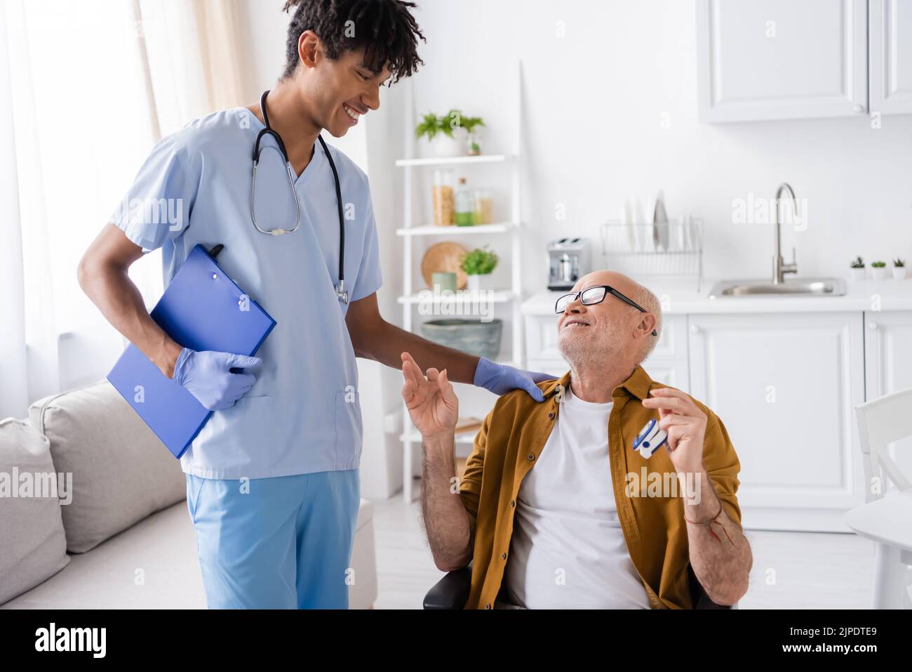 Smiling african american nurse looking at senior patient with pulse