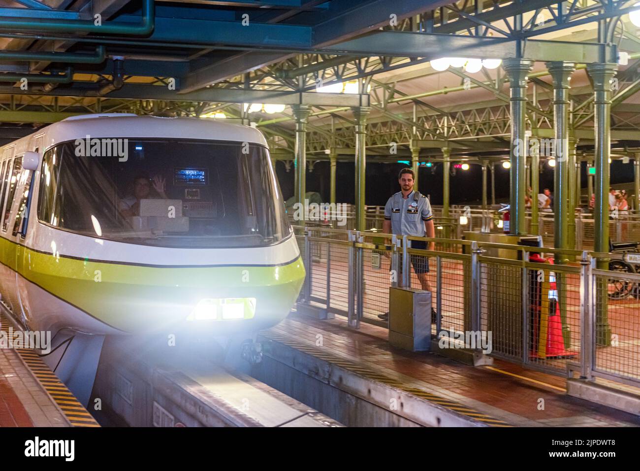 Light train arriving at a station of the monorail system. It is night time so the headlights are on. Stock Photo