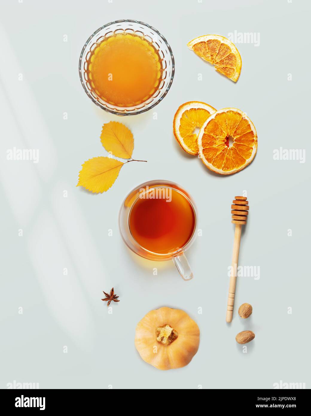 Autumn food. Herbal tea, honey, dry oranges and spices on a blue background with autumn leaves. Immune boosting food, cozy meal. Flat lay Stock Photo