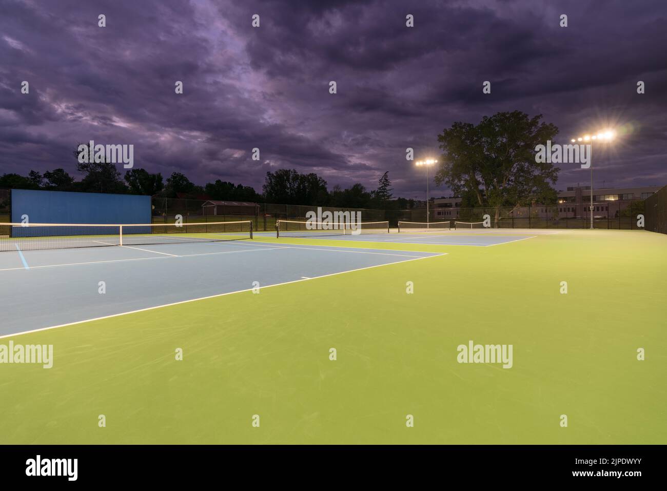 Evening photo of new outdoor blue tennis courts with pickleball lines Evening photo of new outdoor blue tennis courts with pickleball lines