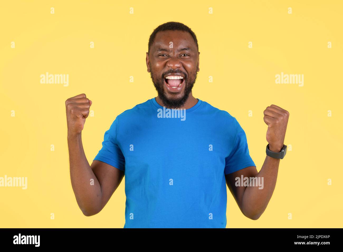 Joyful Black Guy Shaking Fists In Joy On Yellow Background Stock Photo