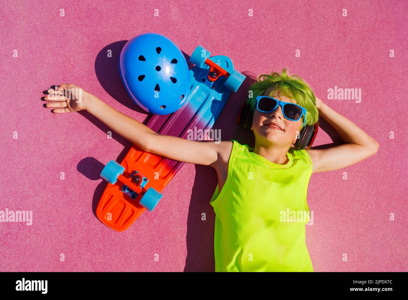 Boy with green hair and skateboard portrait laying at skatepark Stock Photo