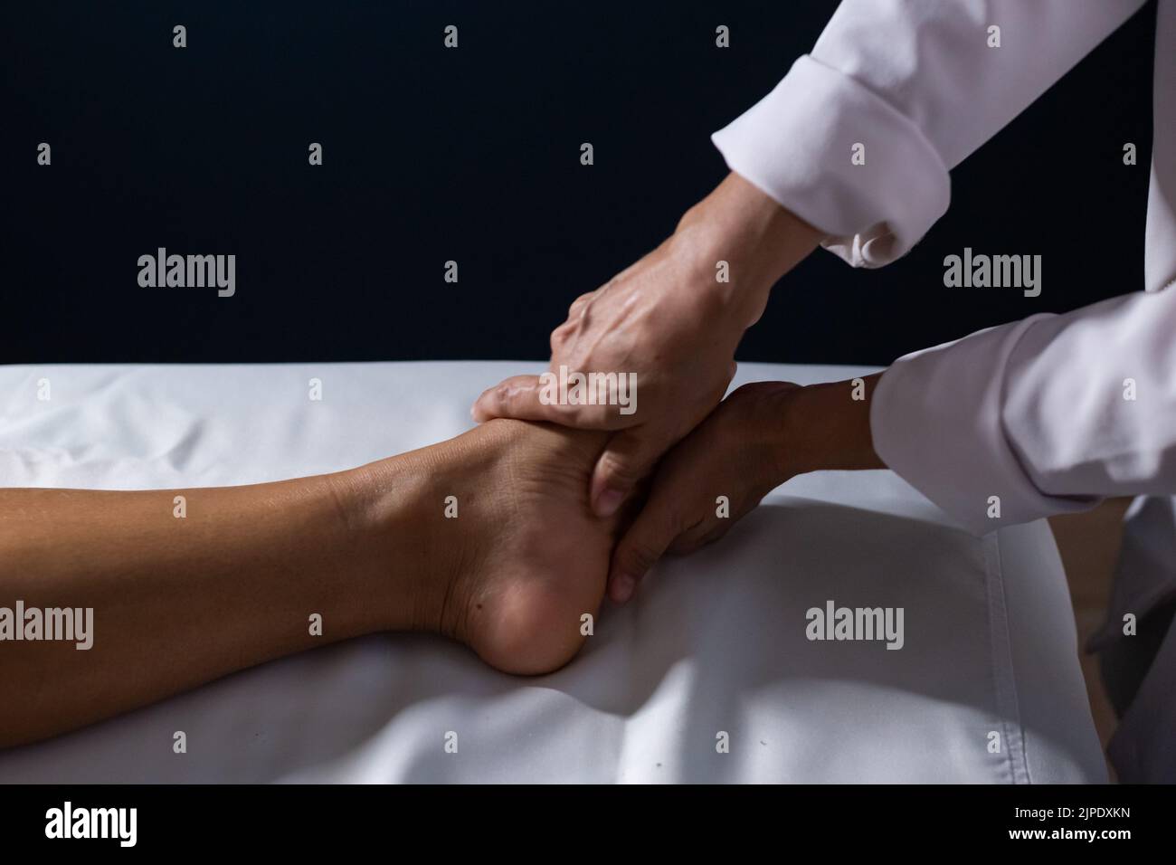 Goiânia, Goias, Brazil – July 18, 2022: Detail of masseuse hands applying therapeutic massage on the foot of a patient who is lying. Stock Photo