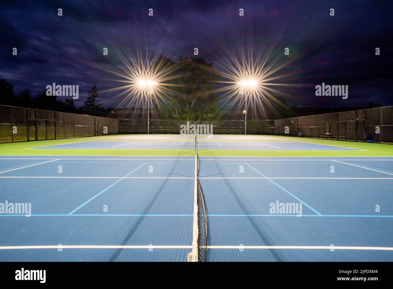 Evening photo of outdoor blue tennis courts with pickleball lines with Evening photo of outdoor blue tennis courts with pickleball lines with