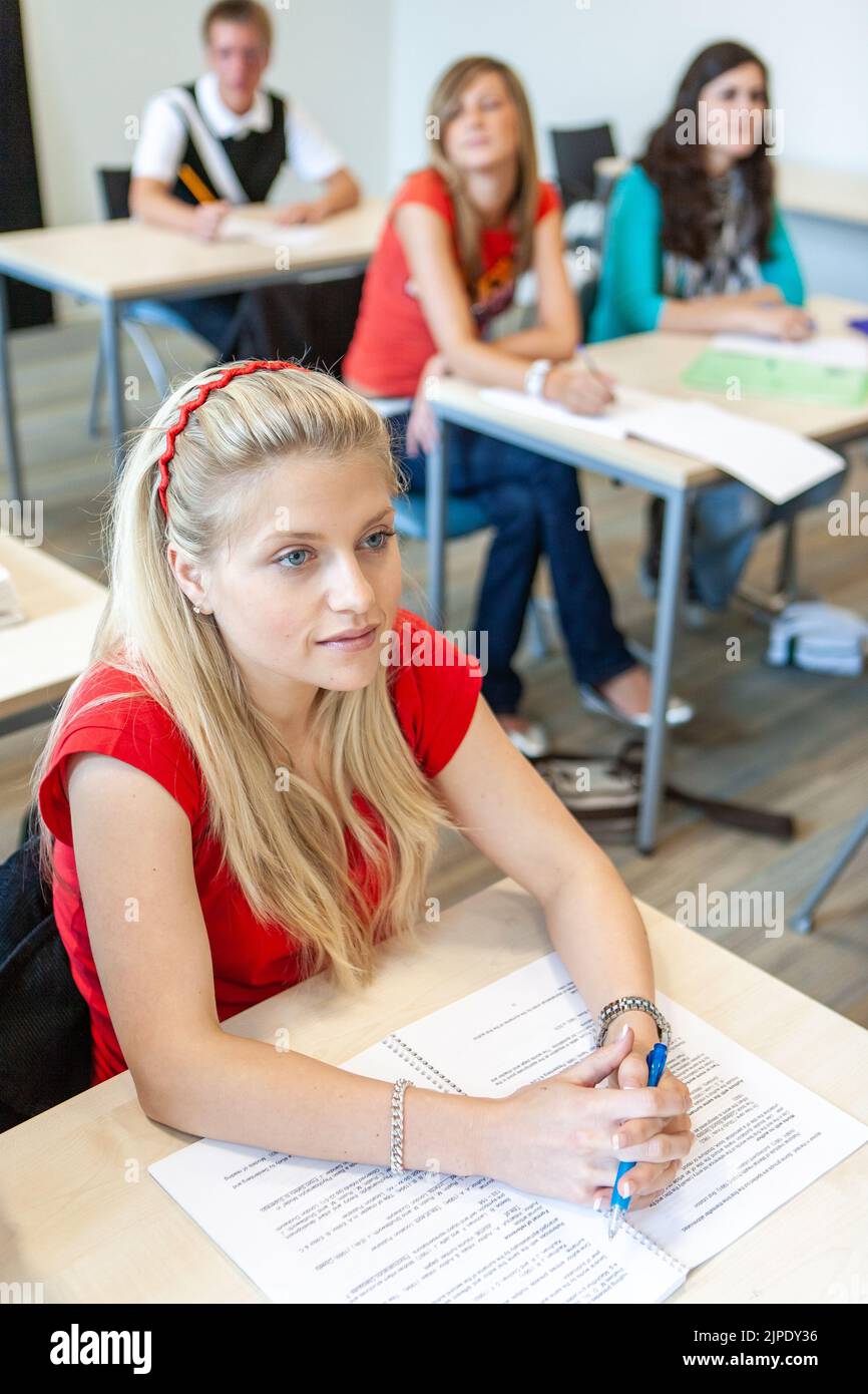 Teenage Students, top of the class. An interested late teenage pupil listening carefully to her teacher. From a series of related images. Stock Photo
