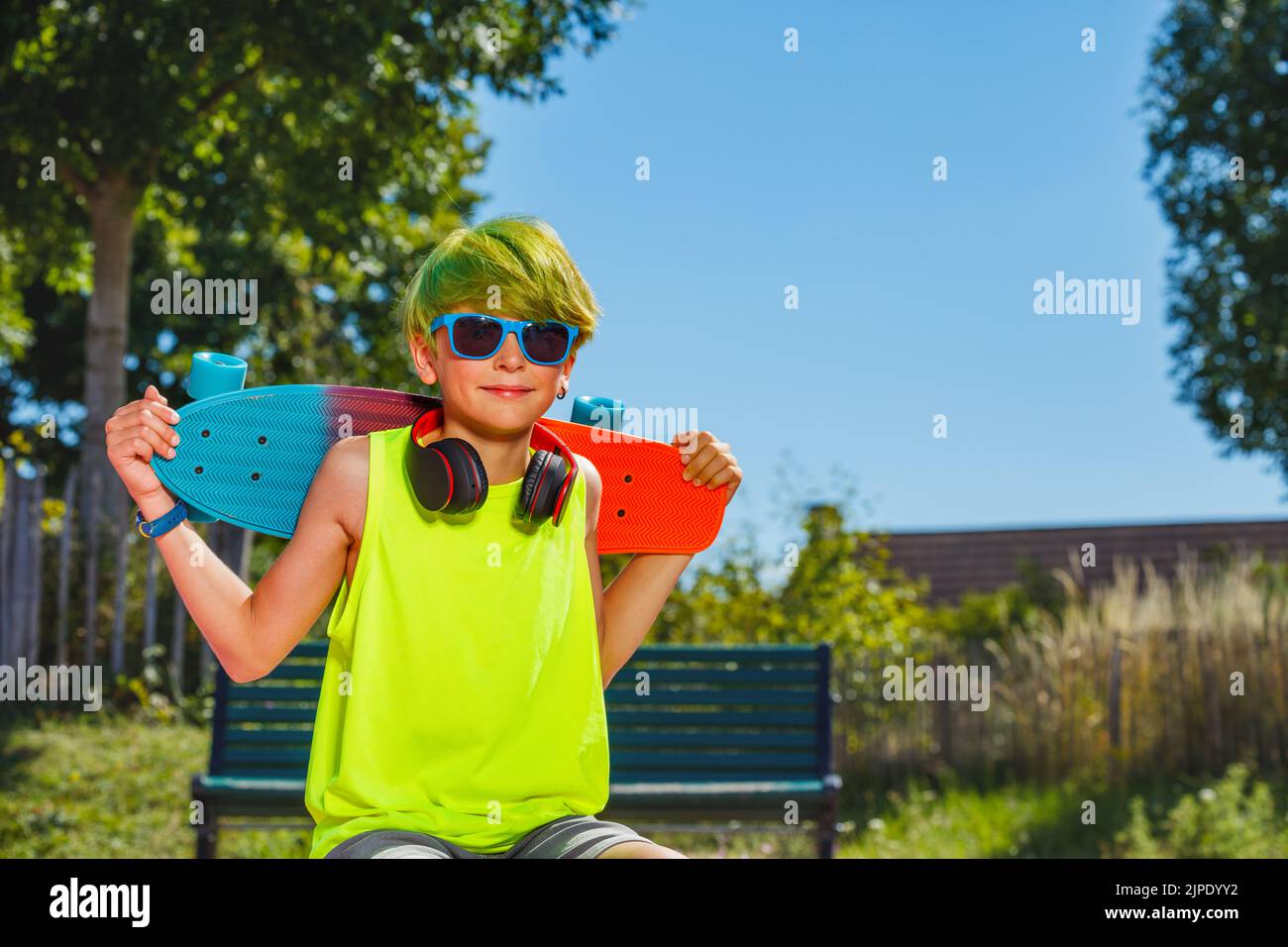 Portrait of a boy with skateboard green hair headphones Stock Photo