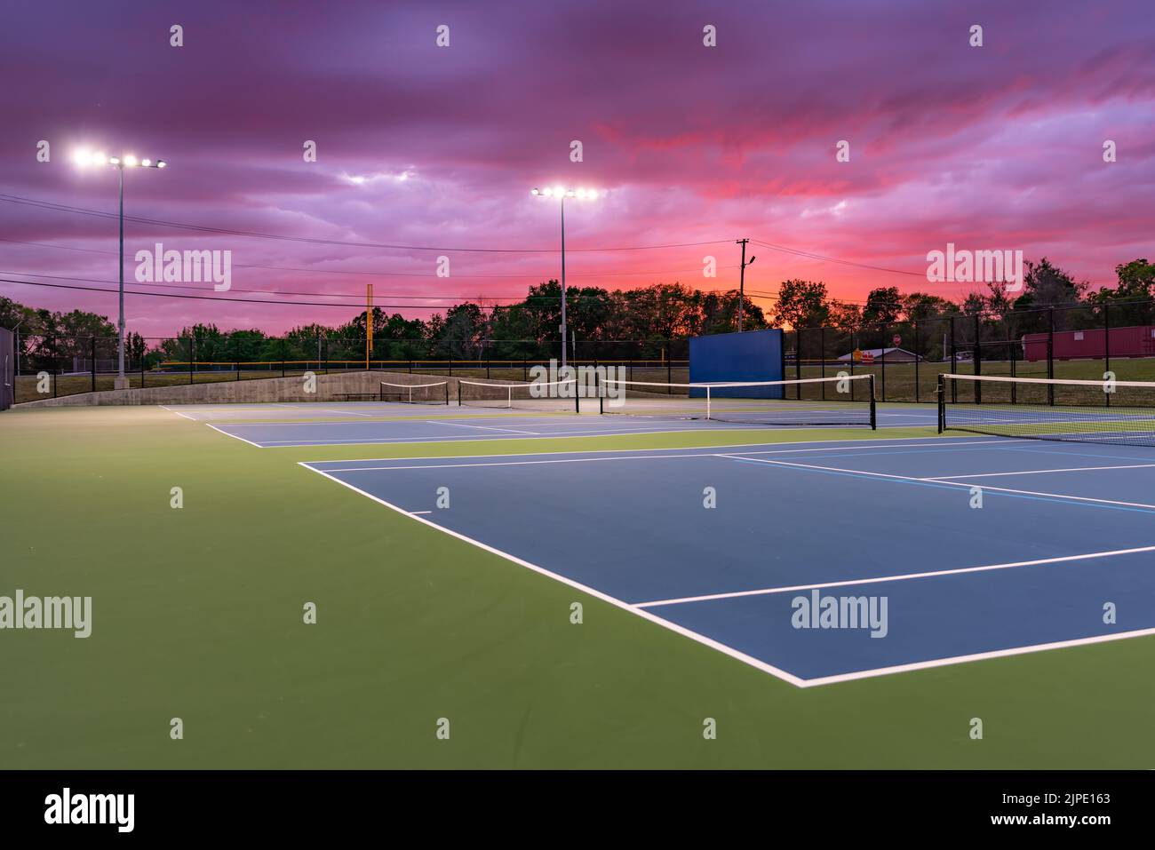 Evening photo of outdoor blue tennis courts with pickleball lines with Evening photo of outdoor blue tennis courts with pickleball lines with