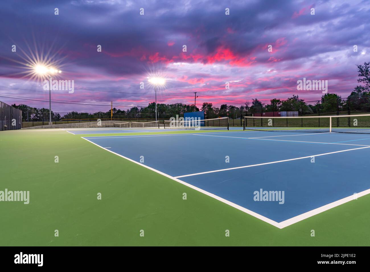 Evening photo of outdoor blue tennis courts with pickleball lines with Evening photo of outdoor blue tennis courts with pickleball lines with