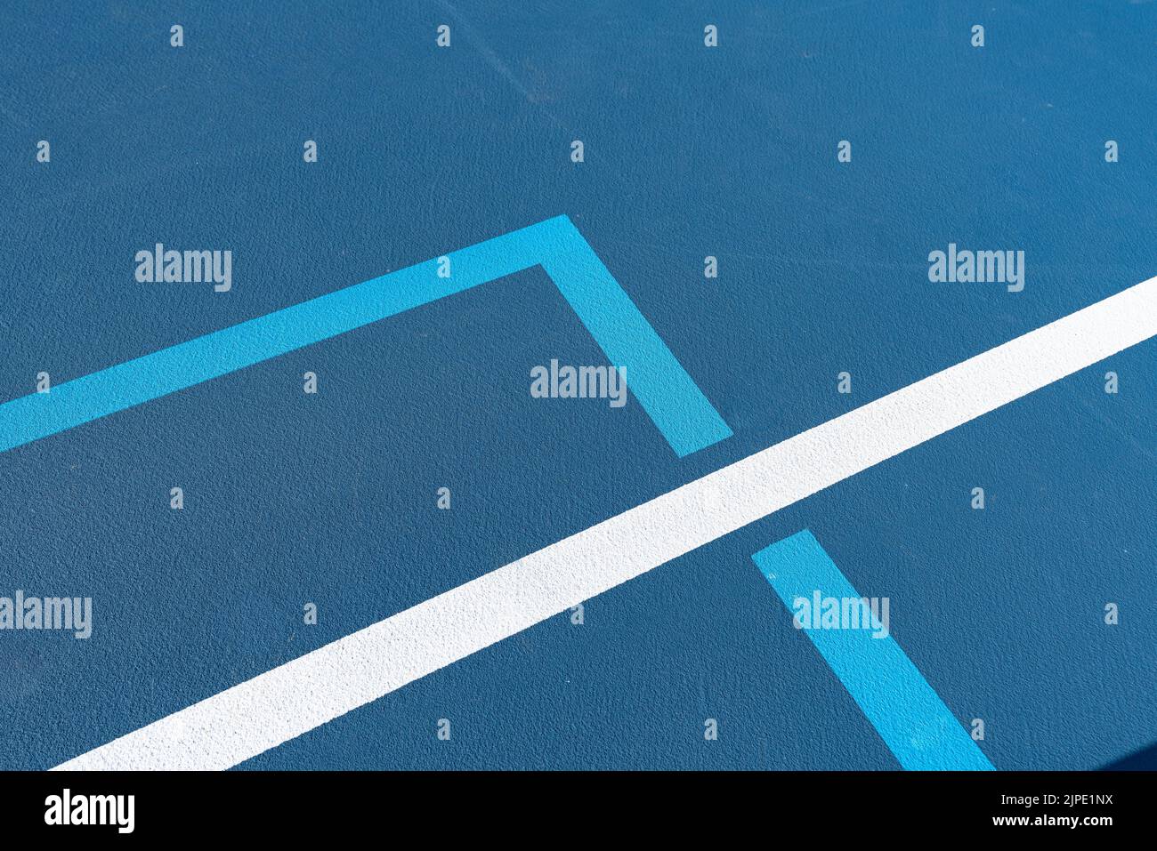 Close up photo of new outdoor blue tennis court with light blue pickleball lines. Stock Photo