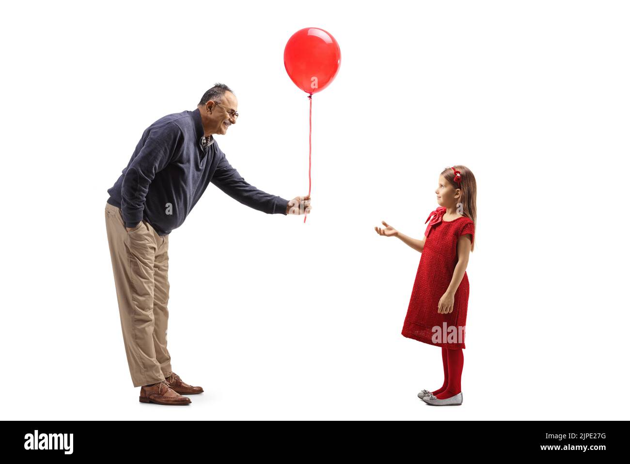 Full length profile shot of a mature man giving a red balloon to a girl isolated on white background Stock Photo