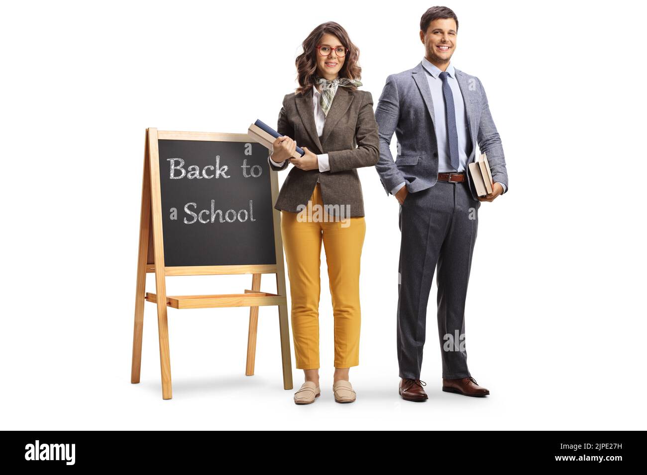 Full length portrait of a male and female teacher standing next to a blackboard with text back to school isolated on white background Stock Photo