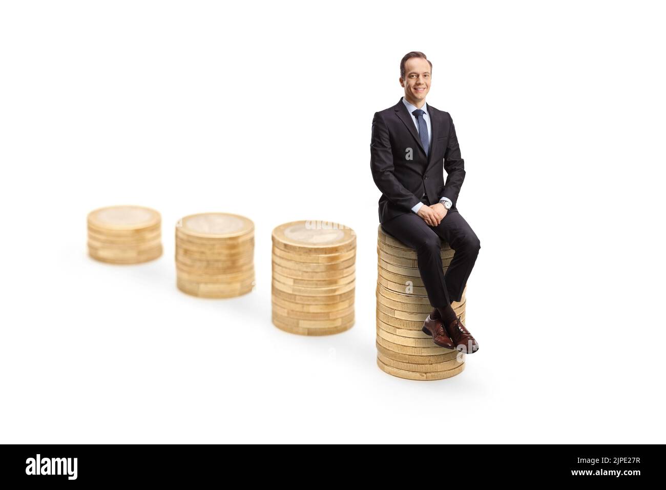 Professional man in suit and tie sitting on a pile of coins and looking at camera isolated on white background Stock Photo