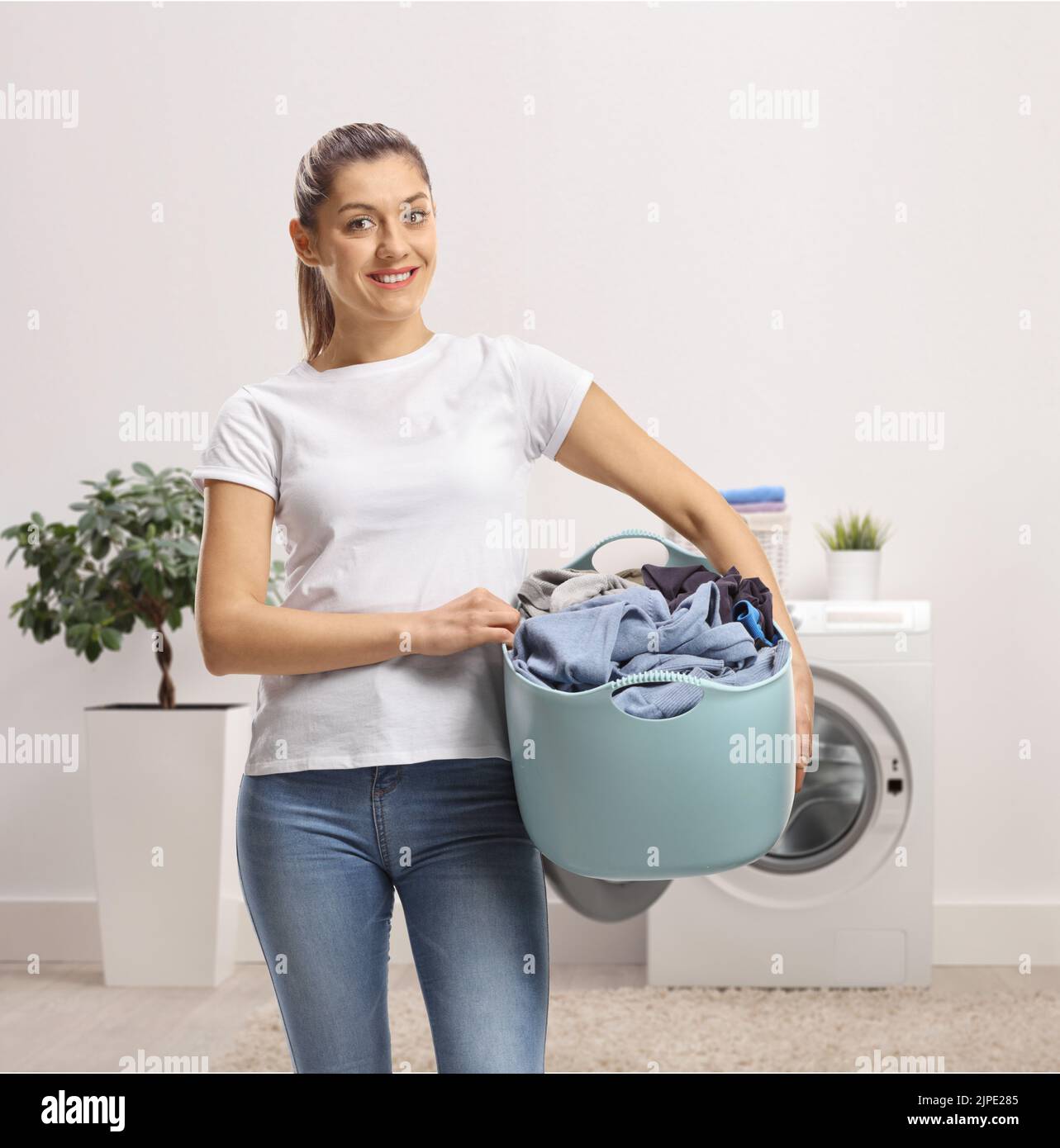 Young female holding a laundry basket inside a bathroom Stock Photo